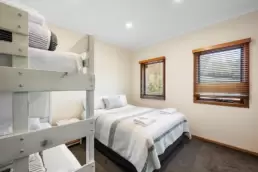 A photo of the second bedroom with a queen sized bed and set of bunk beds 215 Mt Buffalo Pool House. This is a family friendly and pet friendly accommodation option in Porepunkah.